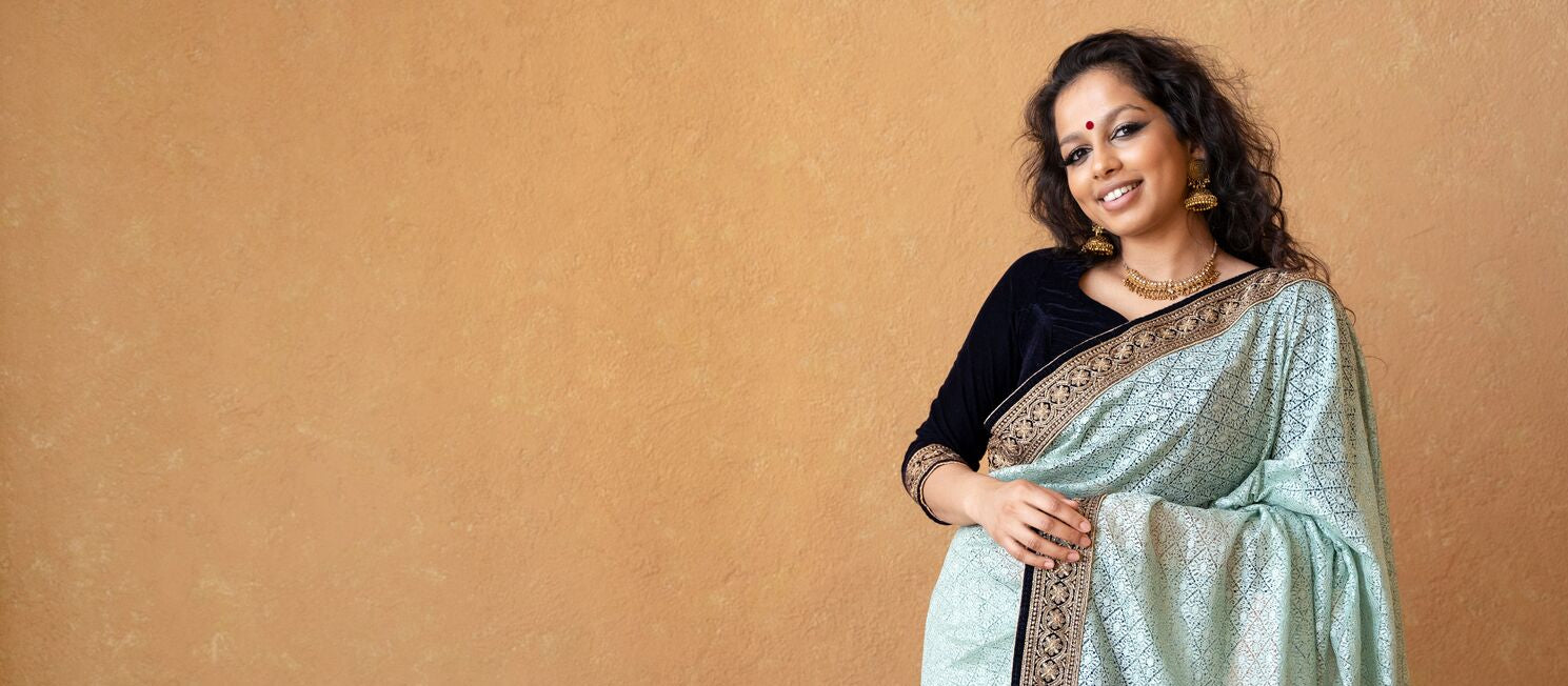 Woman wearing a light blue saree with a brown background